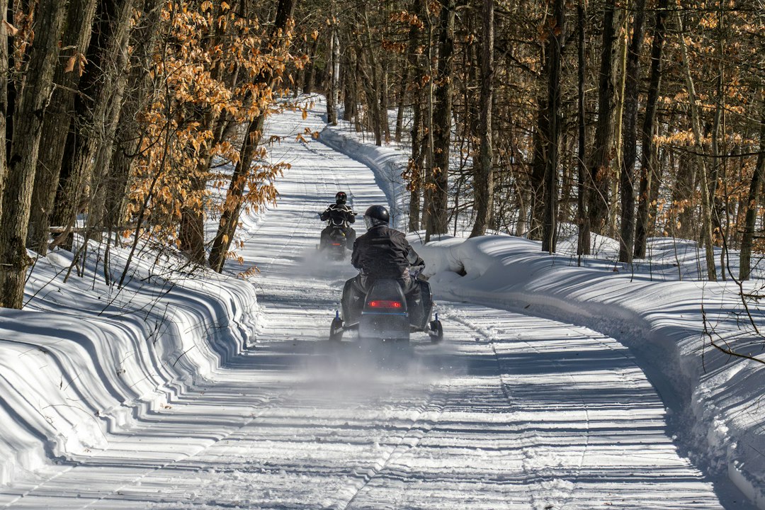 Snowmobilers riding a winter trail. Photo by Chris Robert on Unsplash.